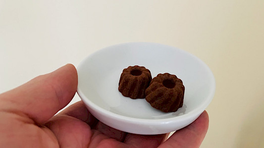 Zwei Pralinen aus Zartbitter-Schokolade mit Trüffeln auf einem weißen Tellerchen