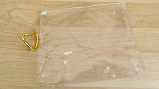 Durchsichtiges Kulturtäschchen mit goldenem Karabiner-Herz als Behältnis fürs Prüfungs-Survival-Kit